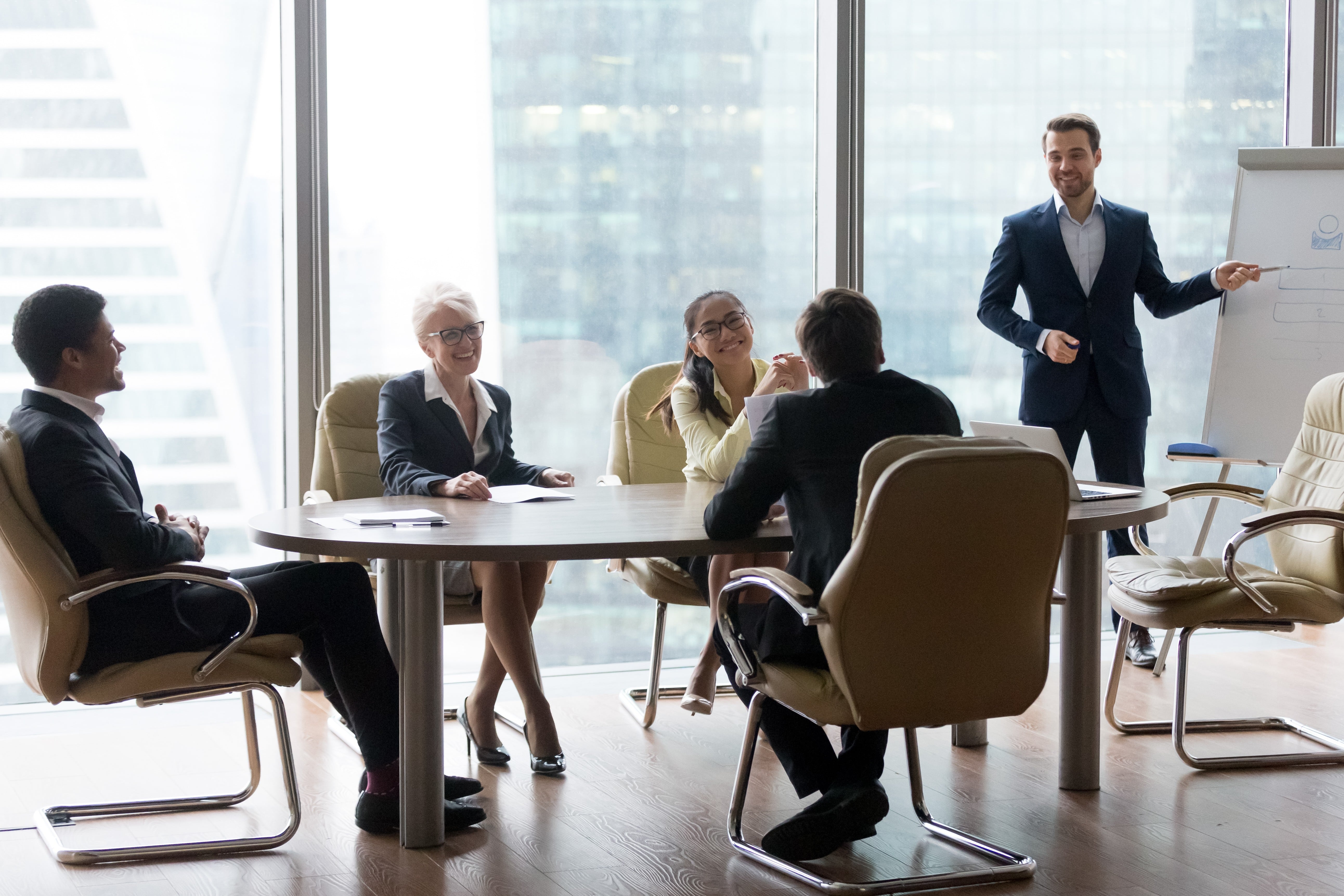 Image depicting a male coach standing in front of a whiteboard in a boardroom, facilitating a strategic guidance session for an executive leadership team